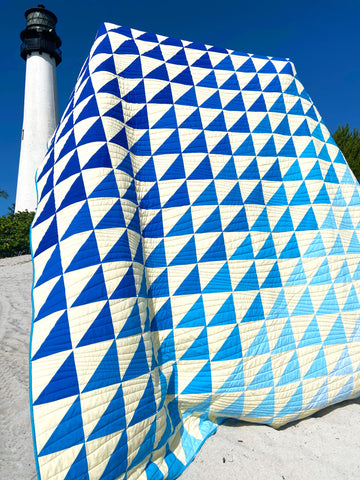 Yellow and Blue Quilt on Beach in Front of Lighthouse
