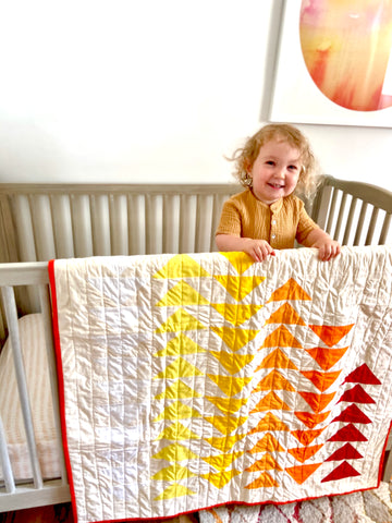 quilt hanging on crib in nursery