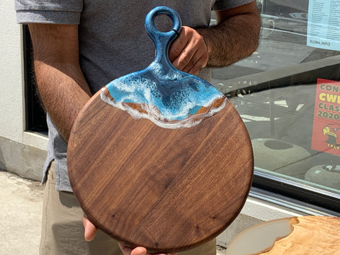 Beautifully crafted cutting board that is also a charcuterie board.  It has blue and white resin on the handle that leads into one side of the board.