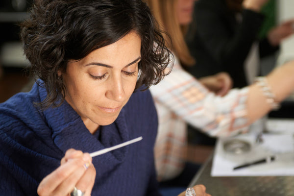 woman testing NOTE fragrances with paper blotter