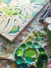 paint palette next to tropical leaves painting