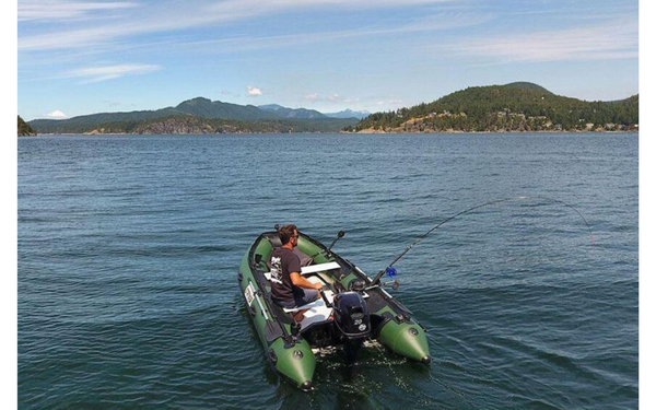 A man fishes from his boat on a big lake. 