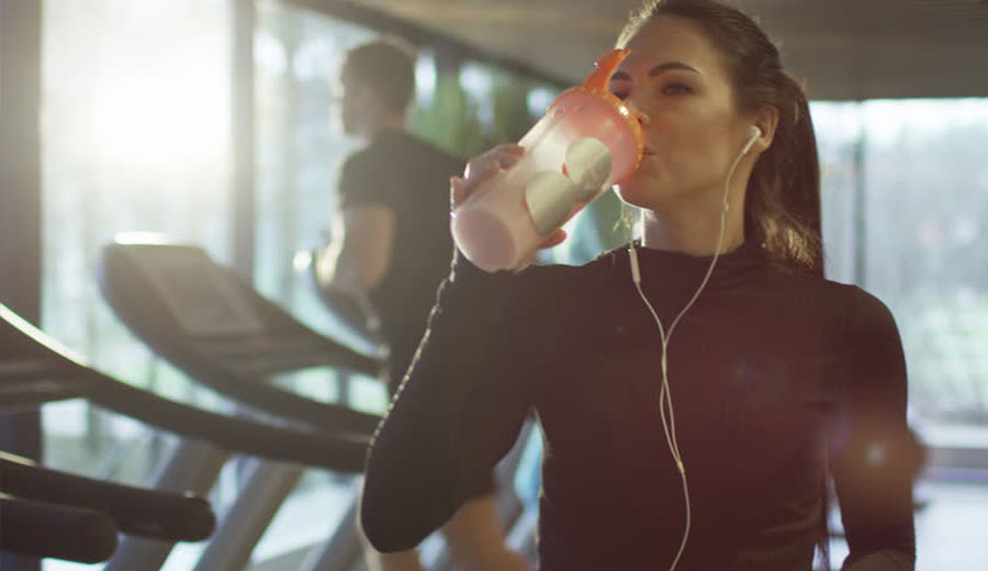 Mujer Bebiendo proteína después de entrenamiento