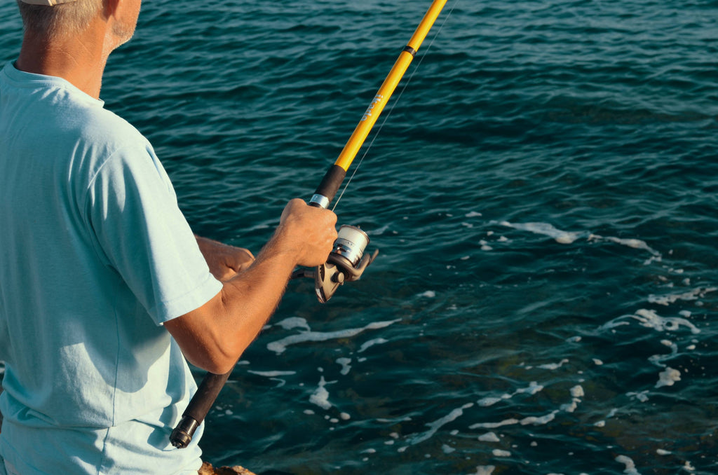 selective focus photography of man holding fishing rod photo