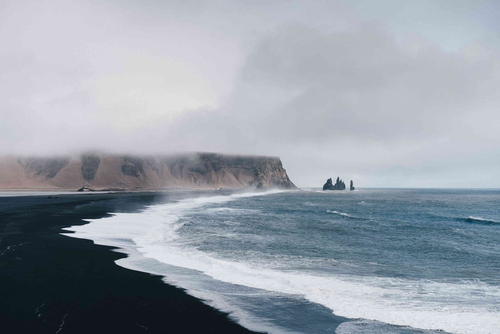 black sand near body of water under the cloudy sky during daytime photo