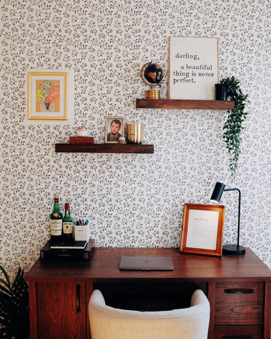A small home office desk against patterned wallpaper