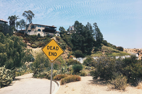 A dead end street next to a home on a hill