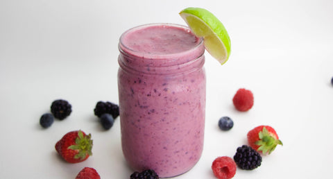 Acerola and berry smoothie in a glass with lime garnish and berries