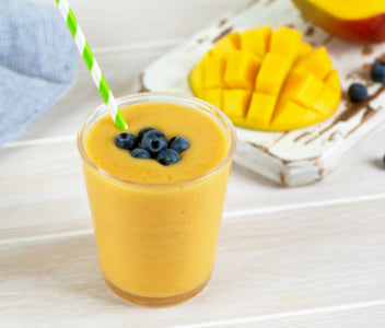 Acerola Mango smoothie poured into glass with straw and berries