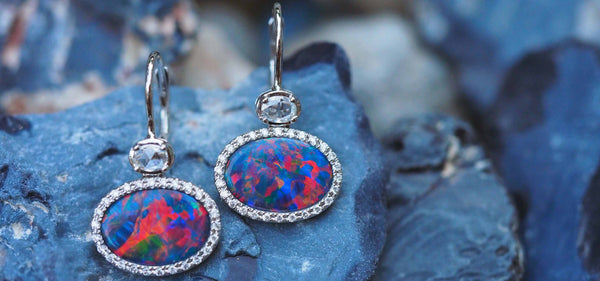 A pair of Australian black opal earrings set against potch opal stone