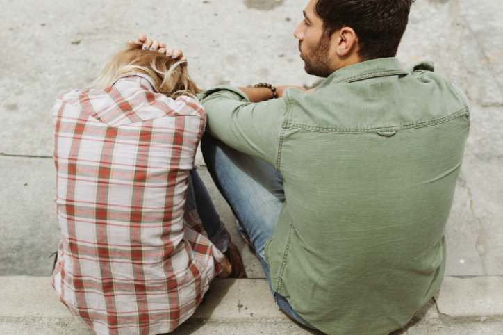 Man and woman sitting on sidewalk regretting decision