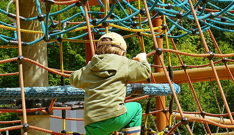 kid playing on climbing net by a playground