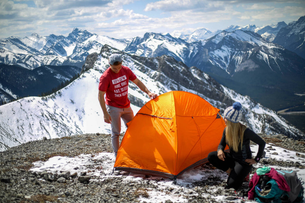 Girl and guy finishing pitching their tent and admiring their work