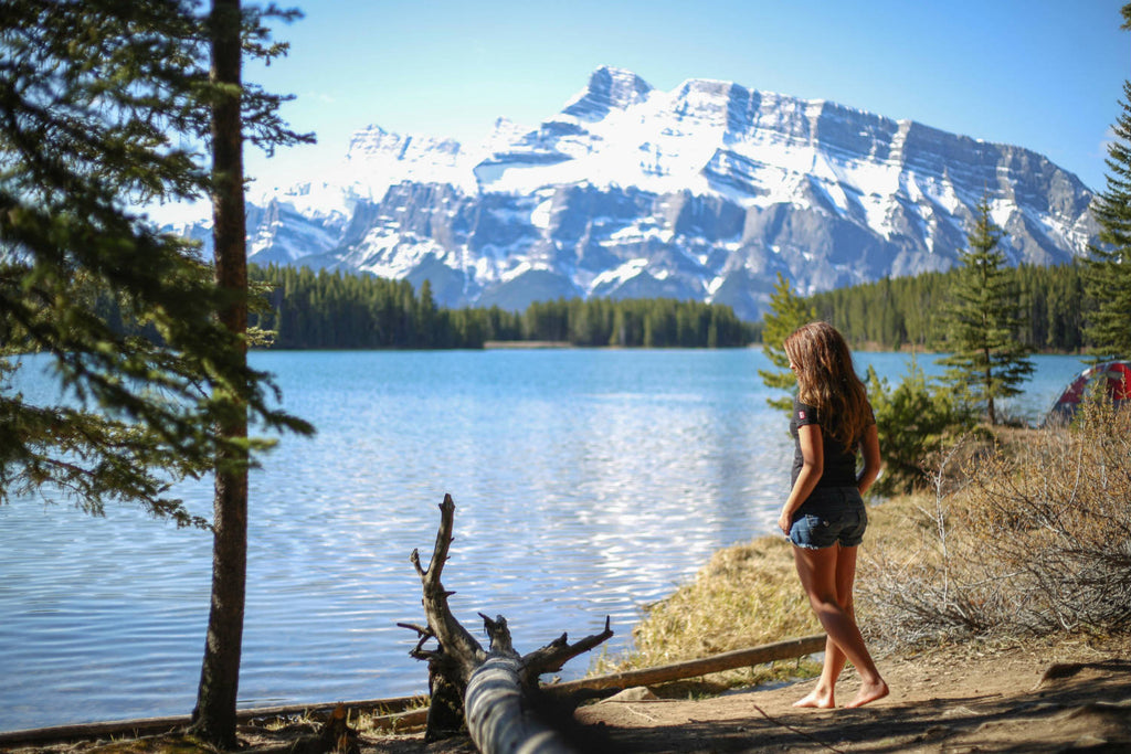 Girl wearing a black v-neck t-shirt standing by a lake admiring the view