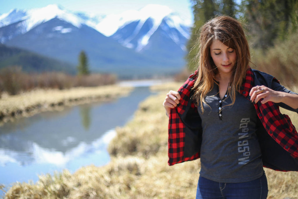 Girl wearing a black mix 5-button henley putting on a vest