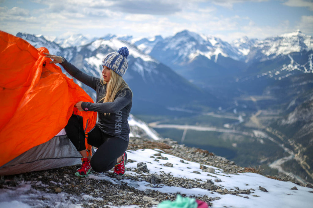 Girl crouched down pitching a tent wearing a black mix 5-button henley