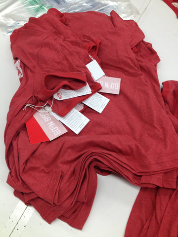 A stack of 60°N 95°W t-shirts with hang tags.