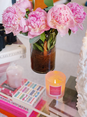 Iridescent pink candle in a holographic vessel next to peonies by Malibu Apothecary
