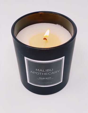 Candle burning in matte black from Malibu Apothecary with a white background