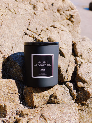 Matte black candle by Malibu apothecary on a rock at the beach in Malibu