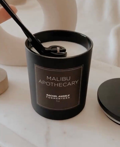trimming a wick on a matte black custom candle by Malibu Apothecary
