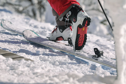 Skier cliping their ski boot into the ski