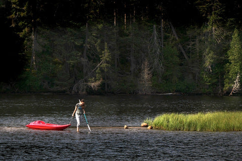 Woman Pulling Kayak Over Shallow Water