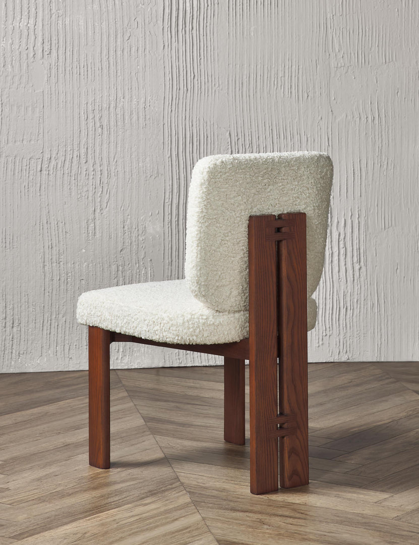 Angled rear view of the Sydney white plush armless dining chair sitting on chevron hardwood flooring with a texture white wall in the background.