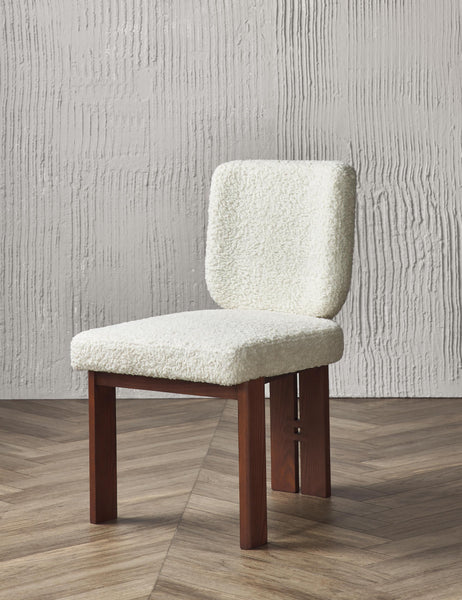 | Angled view of the Sydney white plush armless dining chair sitting on chevron hardwood flooring with a texture white wall in the background.