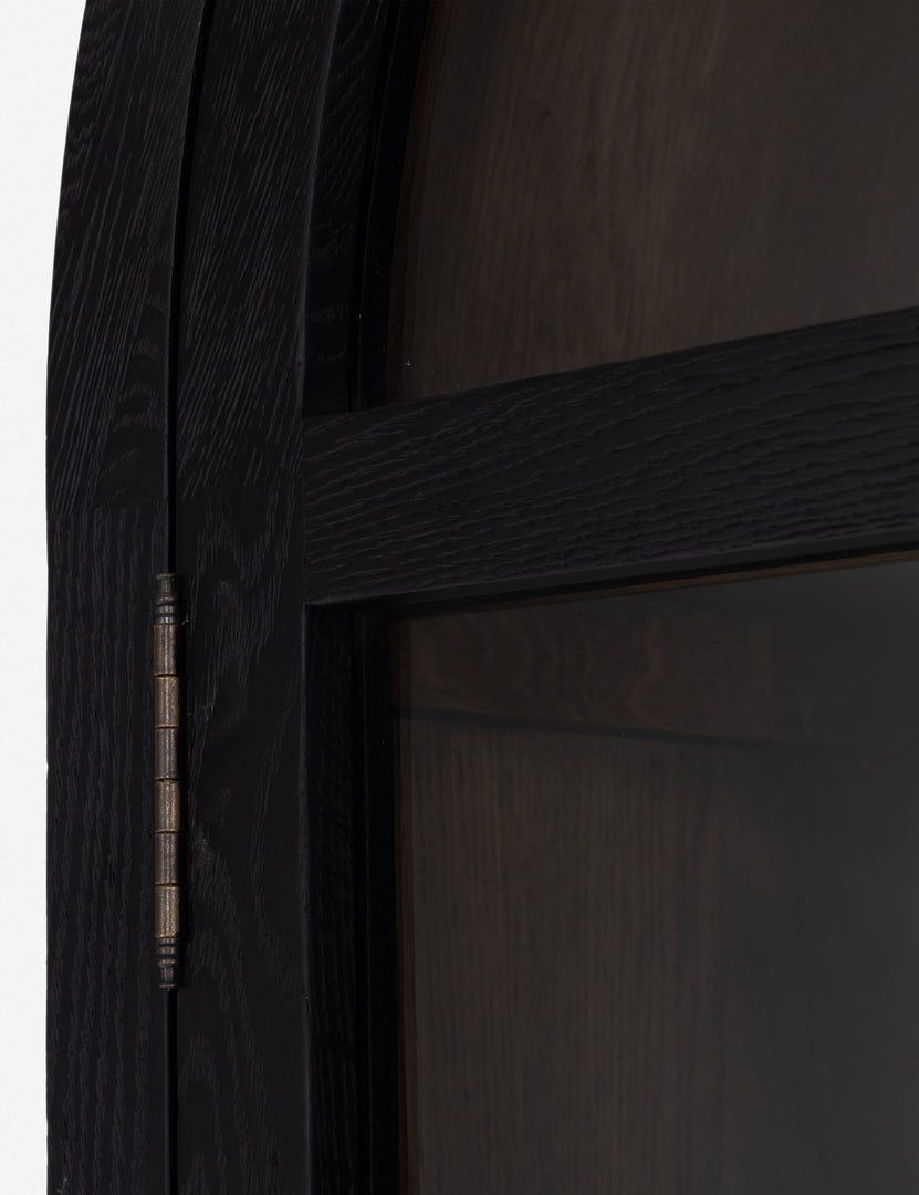 Close-up of the arch on the Apolline black wooden arched curio cabinet with gold door handles