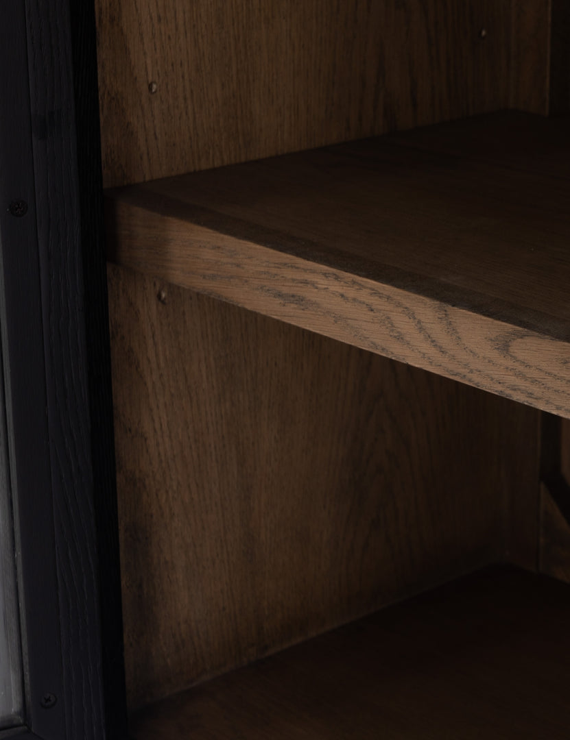 Close-up of the wooden shelving on the Apolline black wooden arched curio cabinet with gold door handles