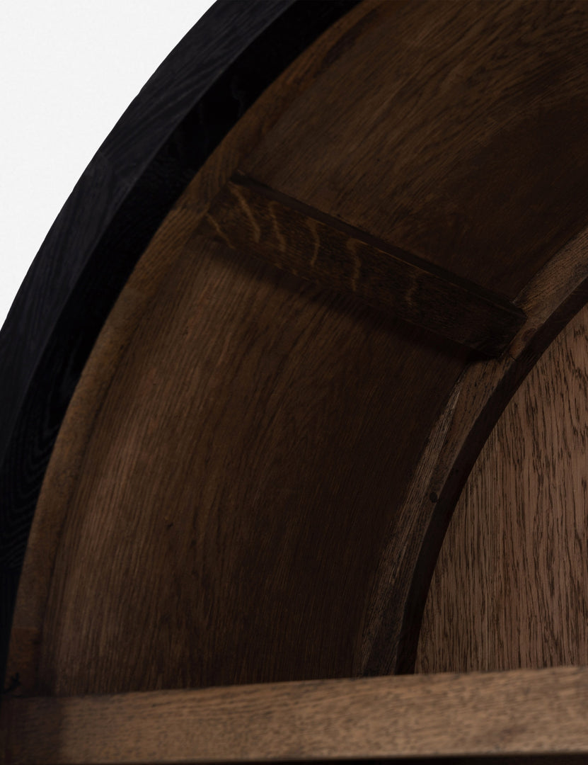 Close-up of the arch and wooden interior of the Apolline black wooden arched curio cabinet with gold door handles
