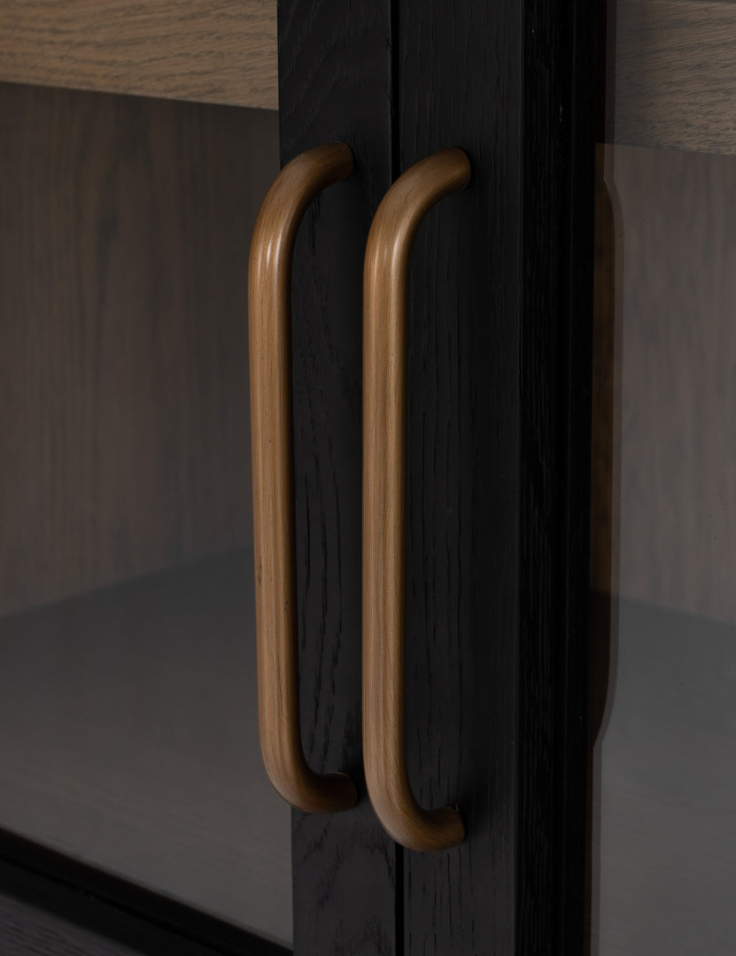 Close-up on the gold door handles of the Apolline black wooden arched curio cabinet