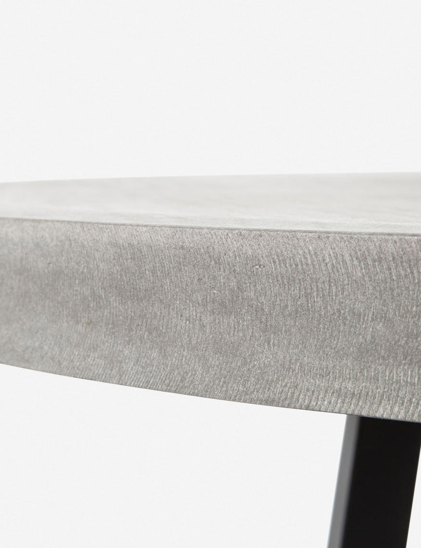 Close-up view of the side of the tabletop on the Agatha indoor and outdoor dining table with lavastone top and black iron base