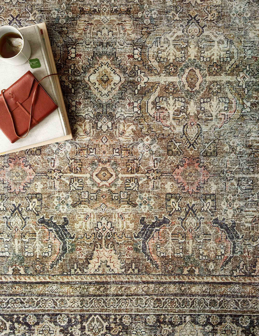 Bird's-eye view of the Dacion distressed dark-toned persian rug with a book sitting atop it