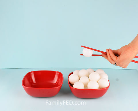 Move balls from one bowl to the next with chopsticks in Backward Ball Drop team game by Family FED