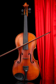 Violin in front of a red stage curtain