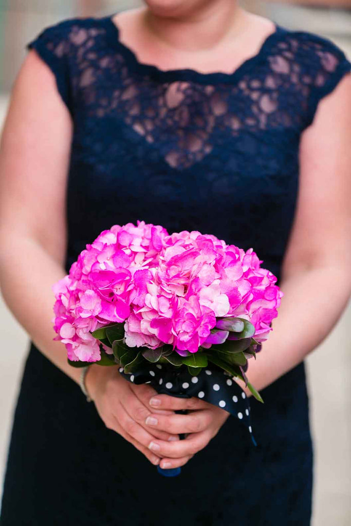 A navy lace bridesmaid dress with a vibrant pink bouquet | A Blue and Pink Rock 'n Roll Wedding