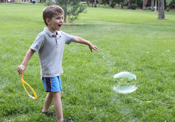 Little kid blowing first big bubble