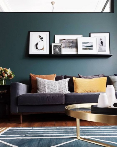 dark green wall with blue sofa and pictures