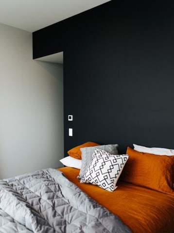 dark grey wall with bed and orange bedding