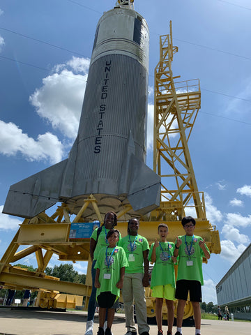 Students posing in front of spaceship.