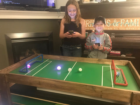 Two children playing with Sphero Minis on activity table.