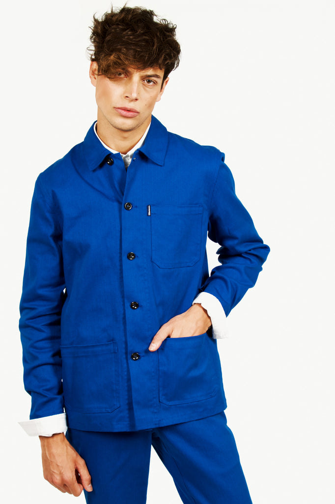 Homme brun nonchalant portant une veste de travail bleu unisexe workwear style vintage parisien