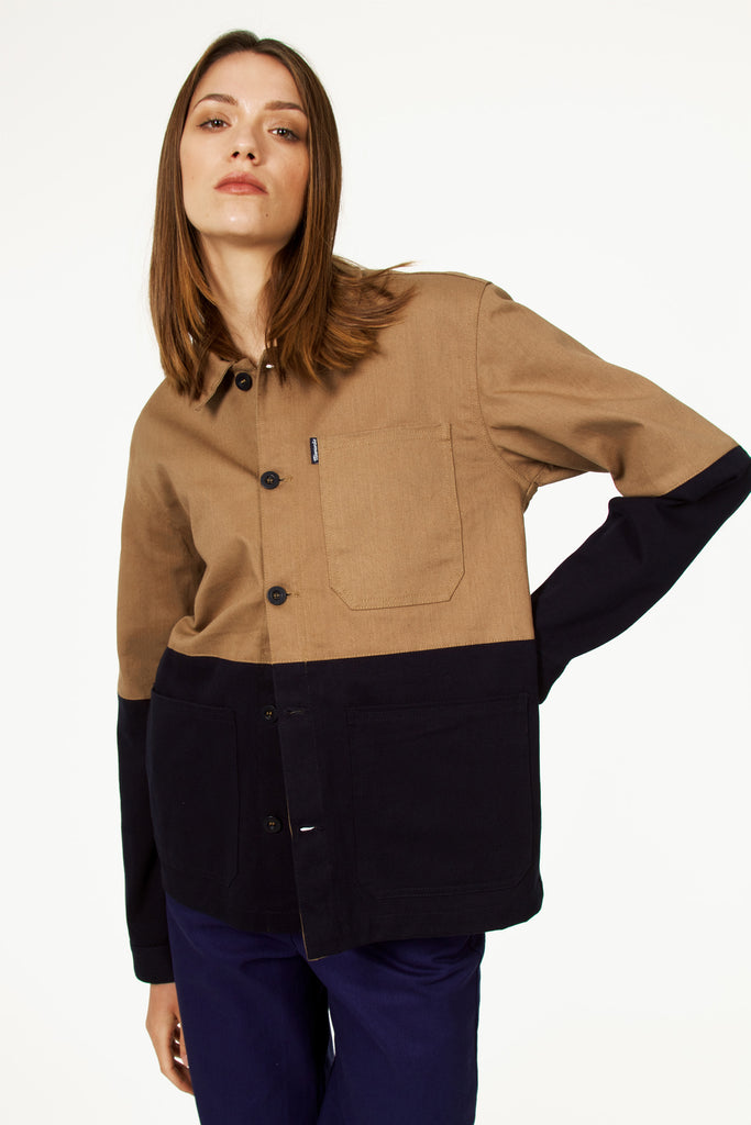 Jeune femme à la beauté naturelle porte une veste bleu de travail bicolore boutonnée en coton style ouvrier, workwear tendance 