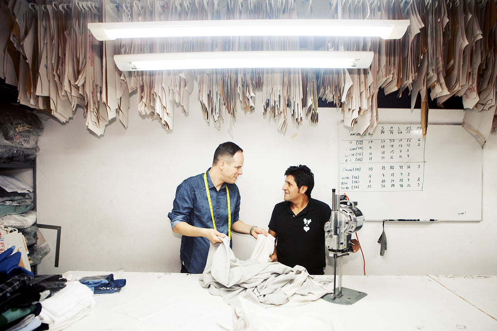 Aurelyen designer fondateur de Misericordia avec un couturier à l'atelier de Lima, discutant et touchant du tissu pour développer la collection