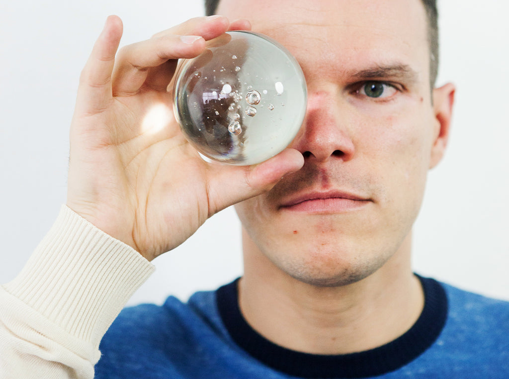 Aurelyen le designer de Misericordia regarde dans une boule de cristal, bulle de verre, regarder vers un avenir plus juste