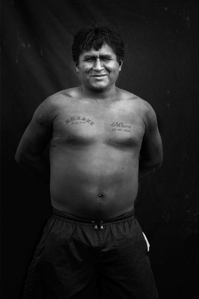 Portrait de Lima, homme posant fièrement les mains dans le dos et tatouage sur le torse