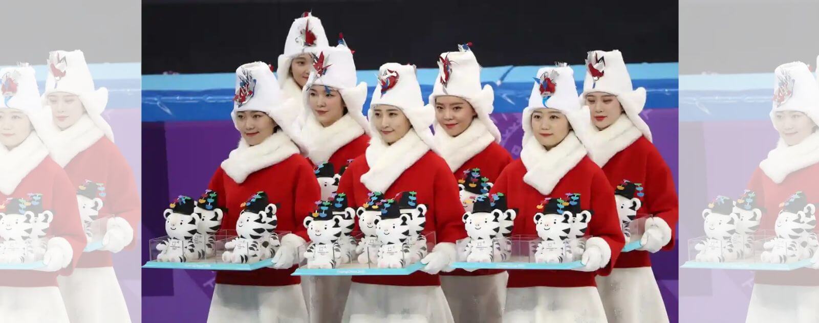 Femmes avec des Manteaux Rouges et des Plateaux de Peluches en forme de Mascotte Olympique Officielle