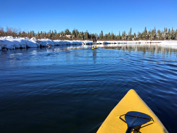 two people paddle boarding in a snow covered lake